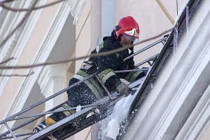 Сотрудник МЧС сбивает лед с крыши. Фото Сергея Серебро