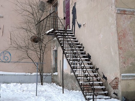 В Витебске на стене одного из двухэтажных домов вы увидите дворника, который метлой сгоняет по лестнице черных кошек. Фото Яны Ильиной