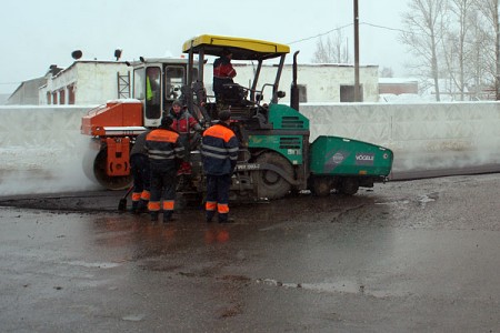 В Витебске в микрорайоне Зеленый городок сносят парники, косят по колено в снегу бурьян и укладывают в снегопад асфальт. Фото Сергея Серебро