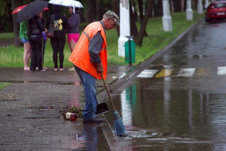 Дворник пытается прочистить ливневку на улице Ильинского в Витебске. Фото Сергея Серебро