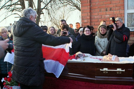 Уладзімір Арлоў накрывае труну бел-чырвона-белым сцягам. Развітанне з Рыгорам Барадулінам перад пахаваннем ў Ушачах. Фота Сержука Серабро