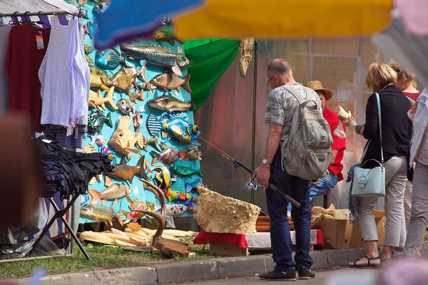 Рыбак рассматривает деревянные фигурки рыб в Городе мастеров на «Славянском базаре в Витебске». Фото Сергея Серебро