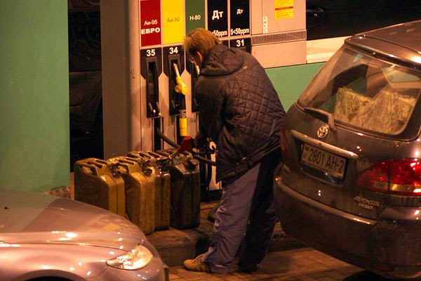 Водитель на автозаправке набирает бензин в канистры перед подорожанием топлив. Фото Сергея Серебро
