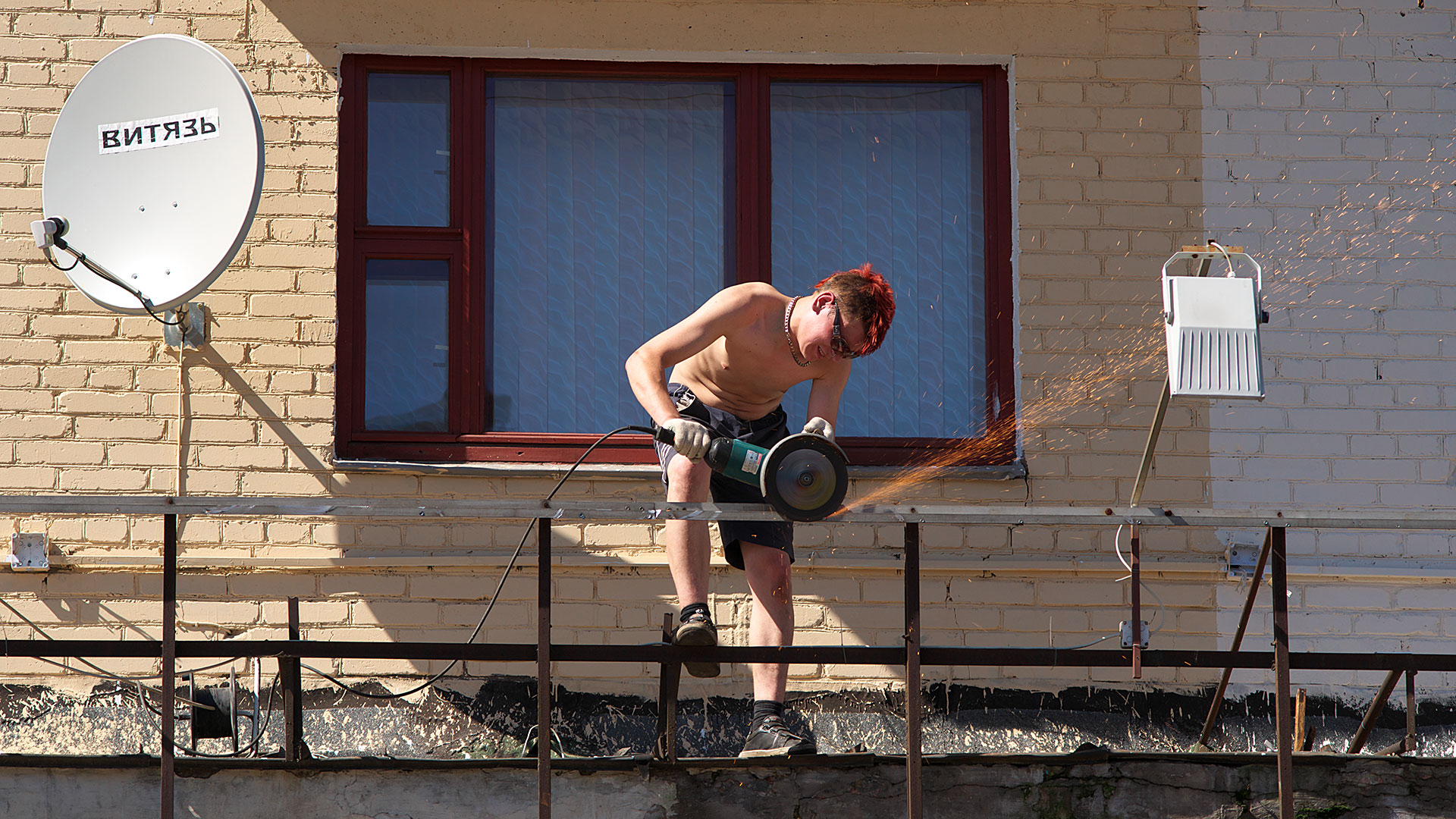Мужчина обрабатывает металлическое ограждение с помощью болгарки УШМ. Фото Сергея Серебро