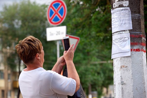 Женщина фотографирует расписание троллейбуса мобильным телефоном. Фото Сергея Серебро