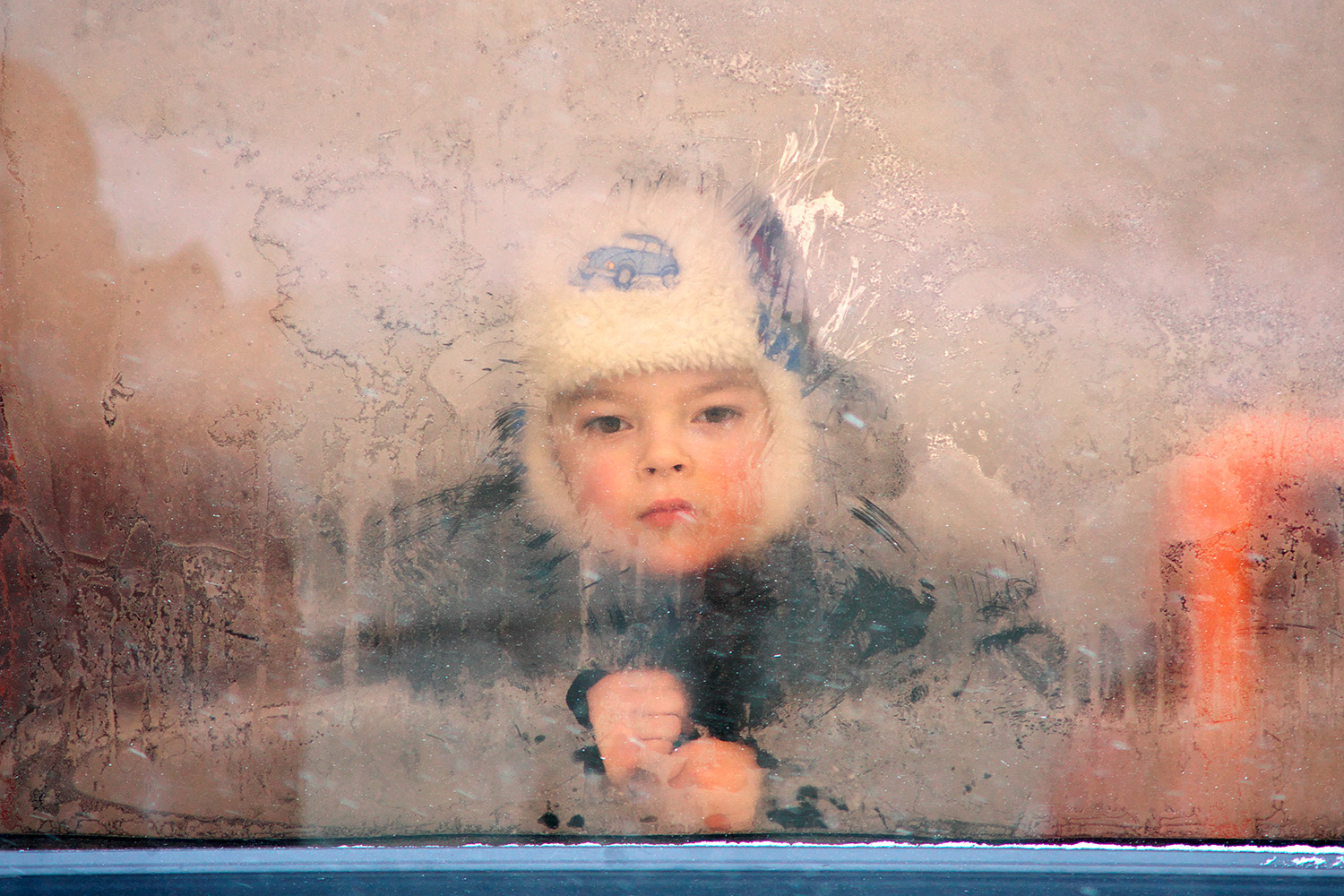 Мальчик смотрит сквозь замерзшее окно городского автобуса во время сильного мороза в Витебске, февраль 2012 года. Фото Сергея Серебро